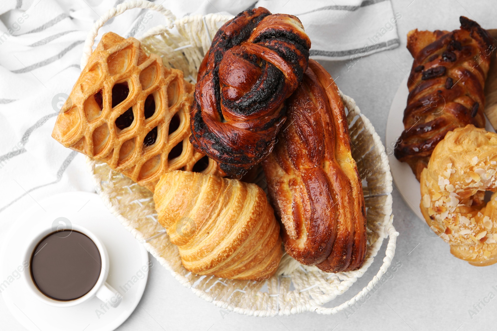 Photo of Different pastries in basket and coffee on light table, flat lay