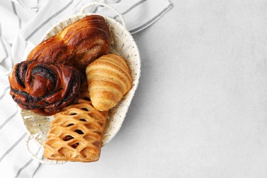 Photo of Different pastries in basket on light table, top view. Space for text