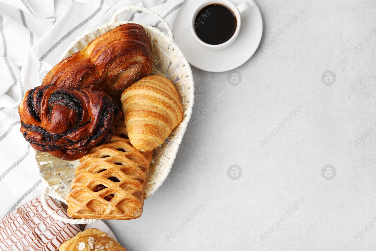 Photo of Different pastries in basket and coffee on light table, flat lay. Space for text