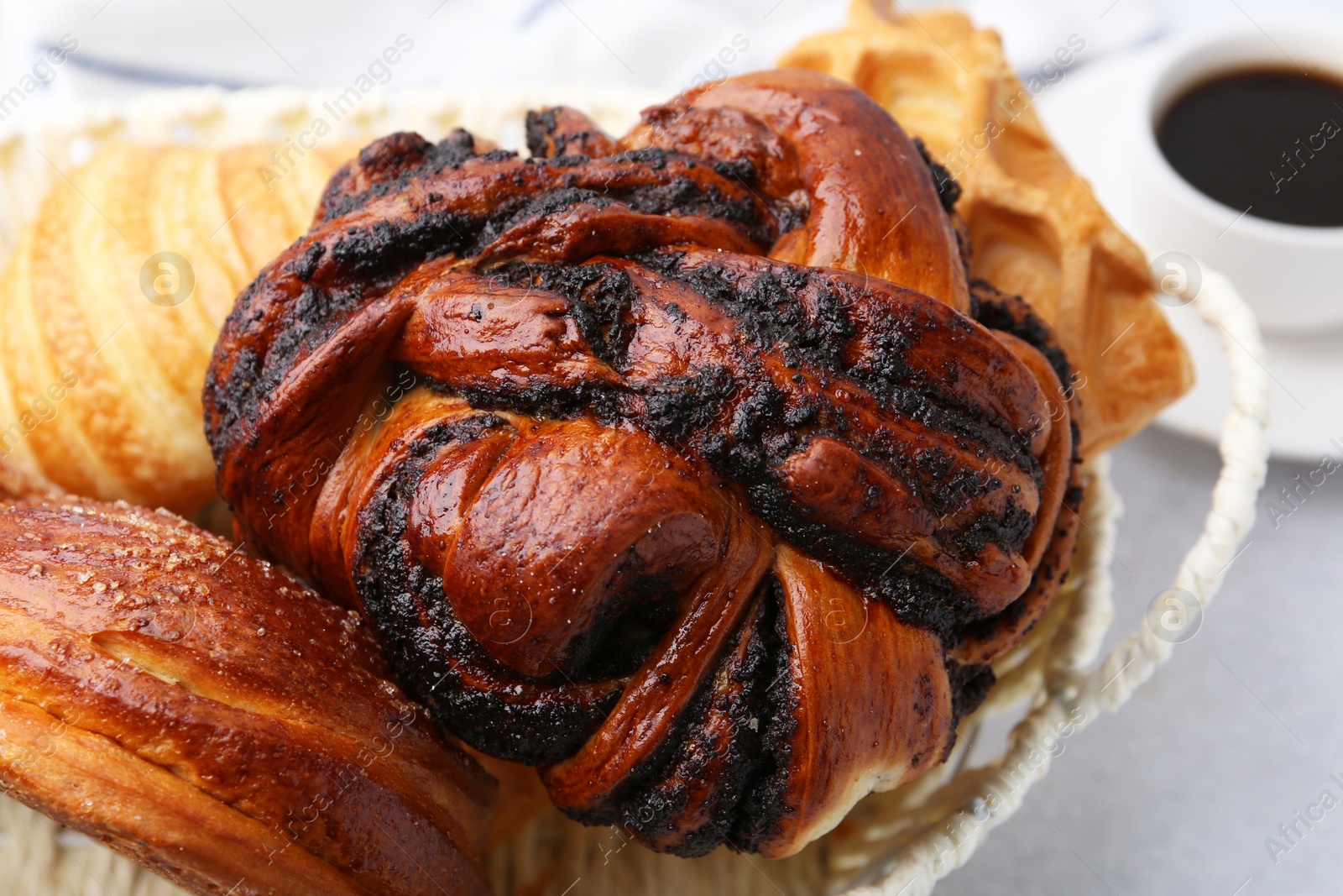 Photo of Different pastries in basket and coffee on light table, closeup