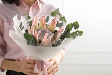 Photo of Woman with beautiful bouquet against light wall, closeup. Space for text