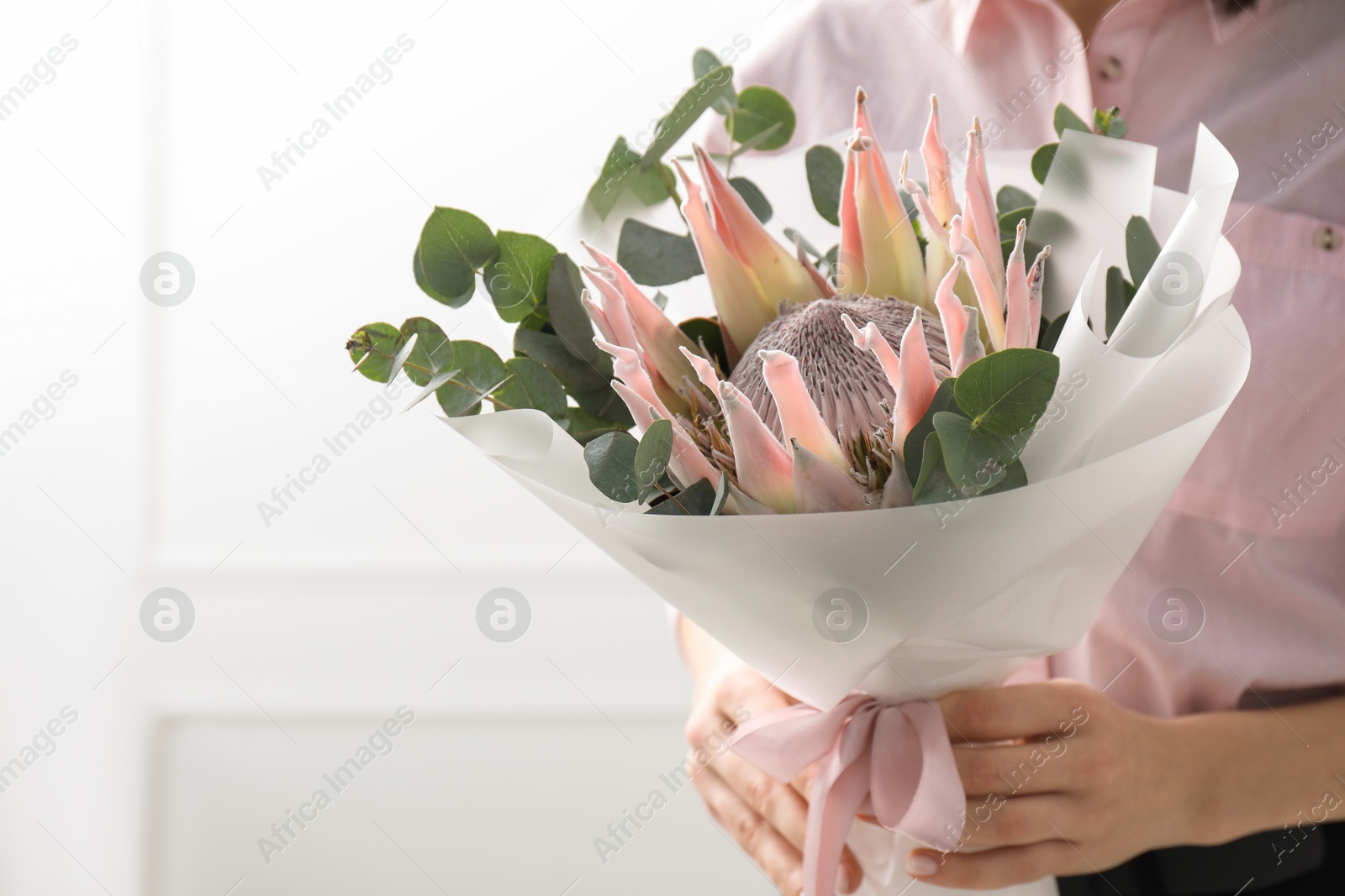 Photo of Woman with beautiful bouquet against light wall, closeup. Space for text