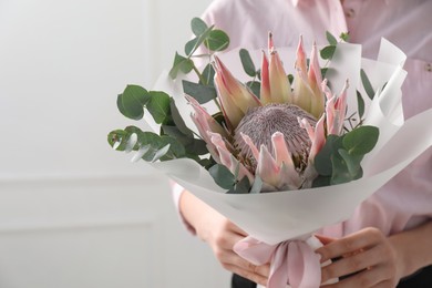 Photo of Woman with beautiful bouquet against light wall, closeup. Space for text