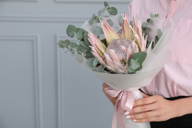 Photo of Woman with beautiful bouquet against light wall, closeup. Space for text