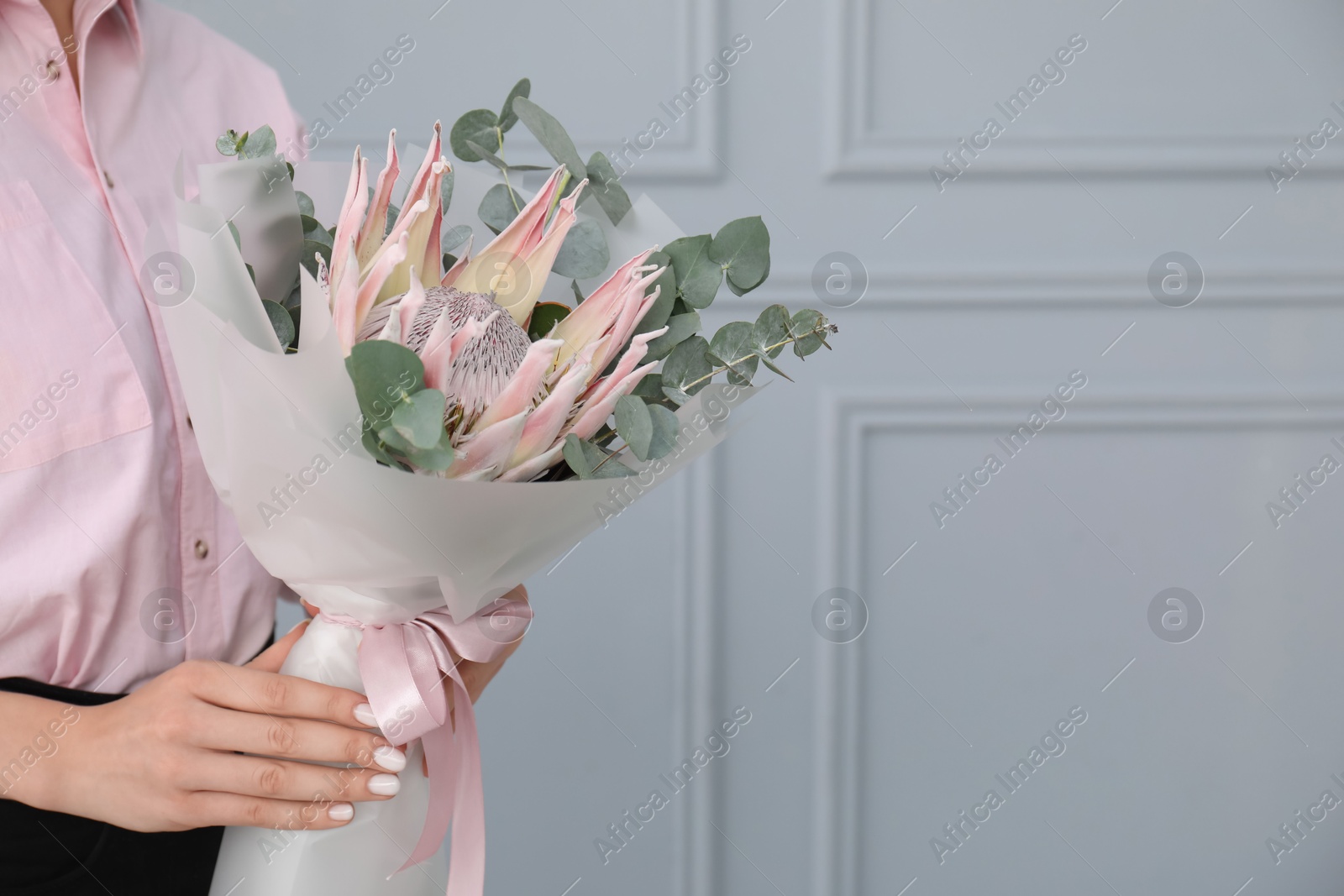 Photo of Woman with beautiful bouquet against light wall, closeup. Space for text