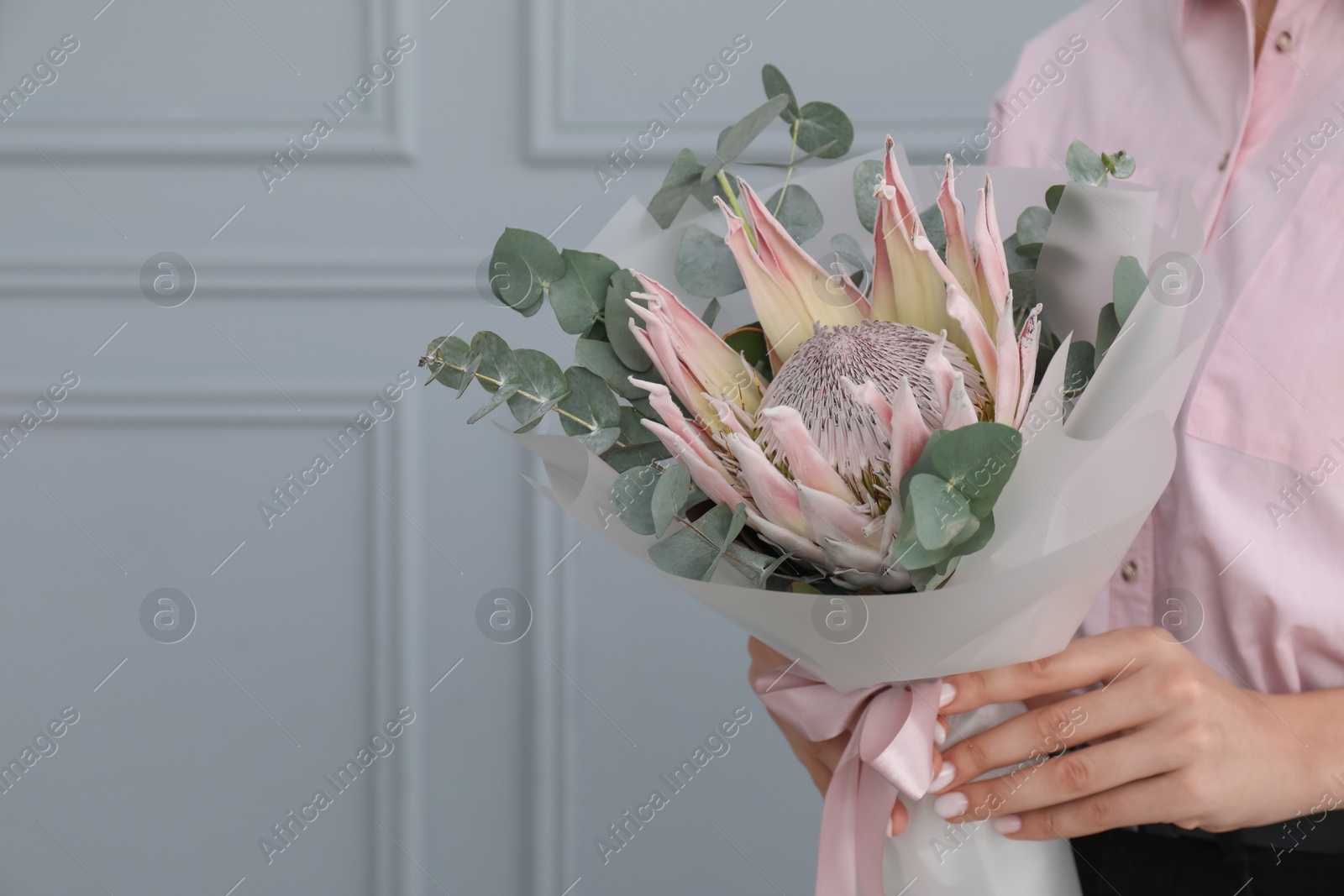 Photo of Woman with beautiful bouquet against light wall, closeup. Space for text