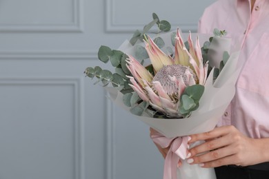 Photo of Woman with beautiful bouquet against light wall, closeup. Space for text