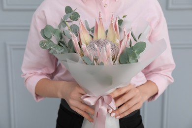 Photo of Woman with beautiful bouquet against light wall, closeup