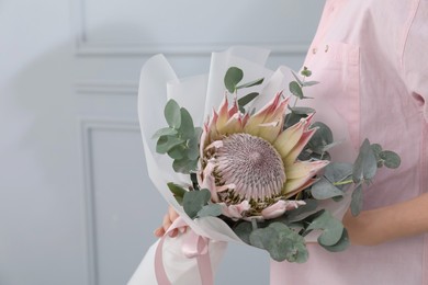 Photo of Woman with beautiful bouquet against light wall, closeup