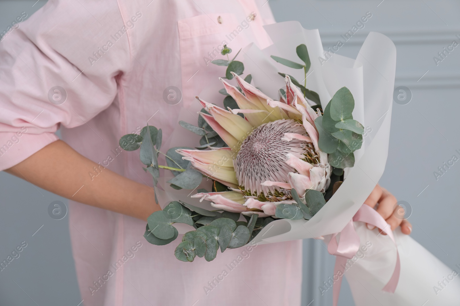 Photo of Woman with beautiful bouquet against light wall, closeup