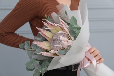 Photo of Woman with beautiful bouquet against light wall, closeup