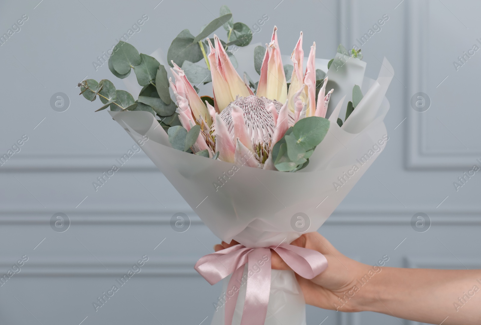 Photo of Woman with beautiful bouquet against light wall, closeup