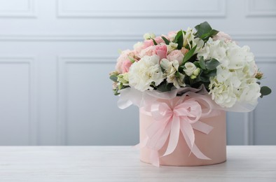 Photo of Beautiful bouquet in box on white wooden table. Space for text