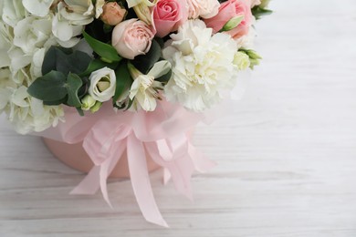 Photo of Beautiful bouquet in box on white wooden table, closeup. Space for text