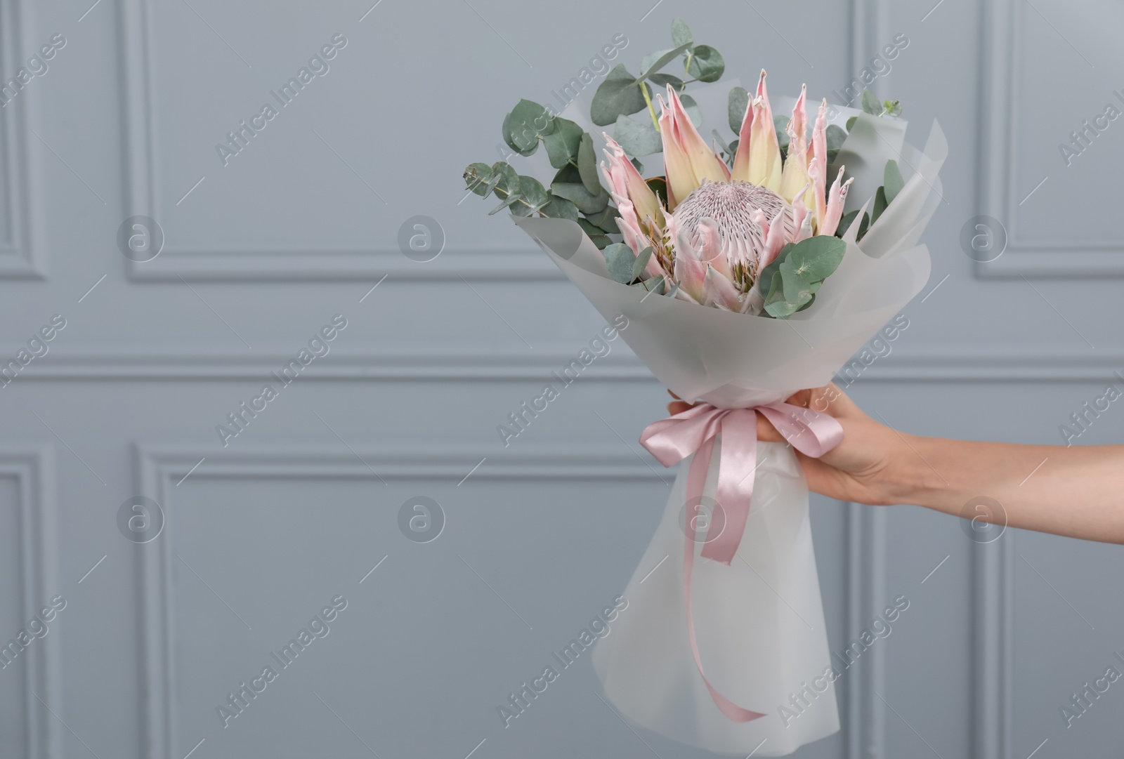 Photo of Woman with beautiful bouquet against light wall, closeup. Space for text