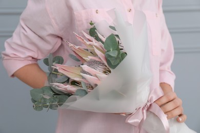 Photo of Woman with beautiful bouquet against light wall, closeup