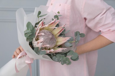 Photo of Woman with beautiful bouquet against light wall, closeup