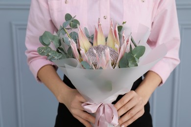 Photo of Woman with beautiful bouquet against light wall, closeup