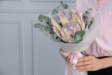 Photo of Woman with beautiful bouquet against light wall, closeup. Space for text