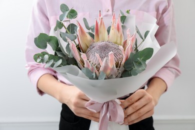 Photo of Woman with beautiful bouquet against light wall, closeup