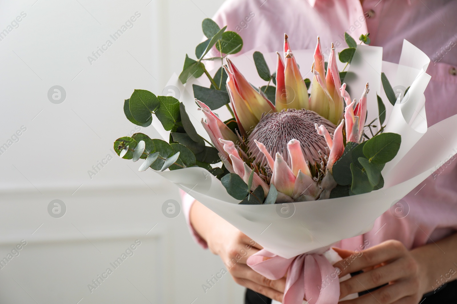 Photo of Woman with beautiful bouquet against light wall, closeup