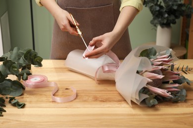 Photo of Florist making beautiful bouquet at table in flower shop, closeup