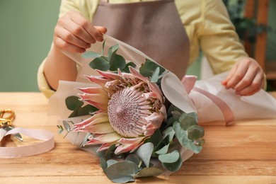 Photo of Florist making beautiful bouquet at table in flower shop, closeup