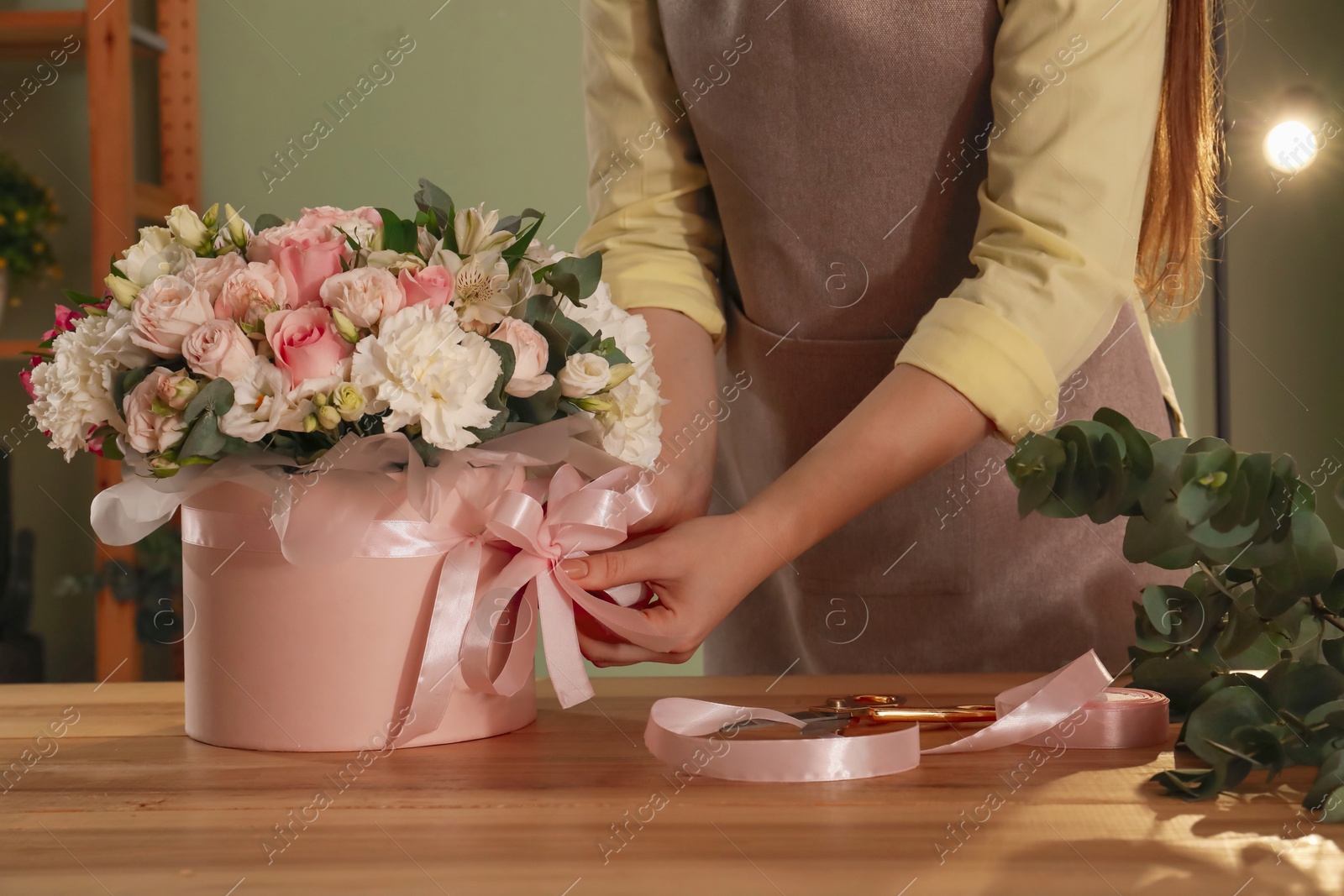 Photo of Florist with beautiful bouquet in box at table indoors, closeup