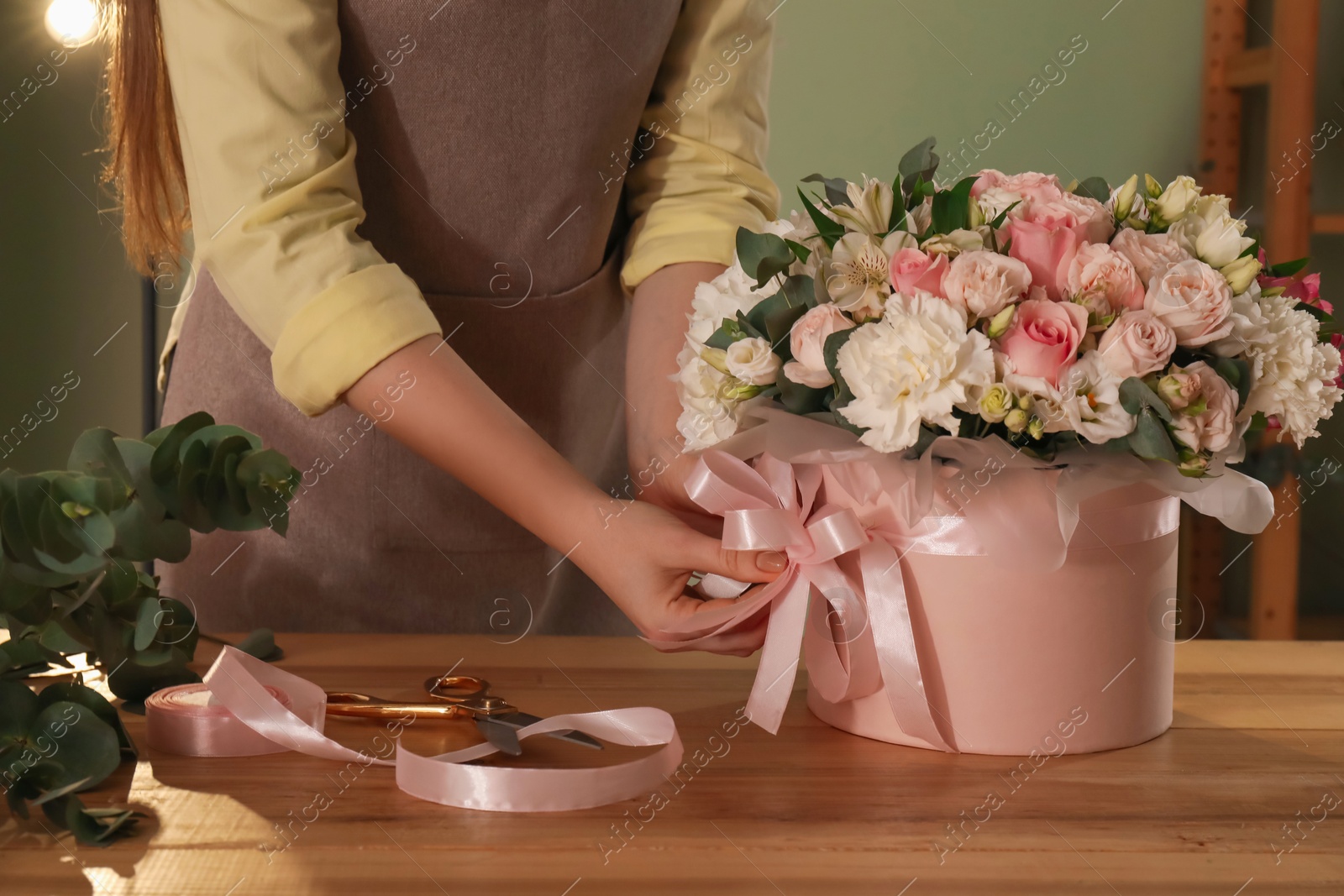 Photo of Florist with beautiful bouquet in box at table indoors, closeup