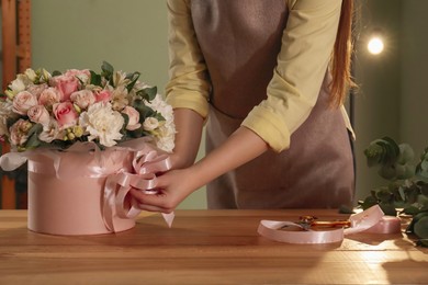 Photo of Florist with beautiful bouquet in box at table indoors, closeup