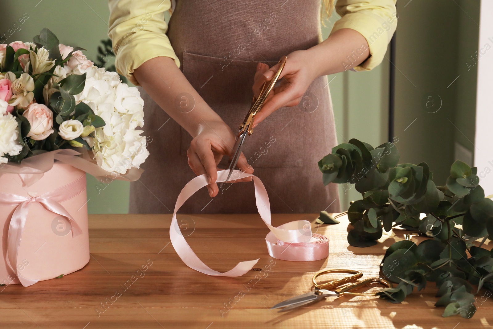 Photo of Florist making beautiful bouquet at table in flower shop, closeup