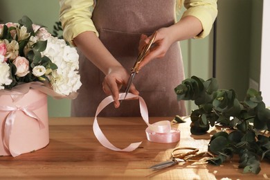 Photo of Florist making beautiful bouquet at table in flower shop, closeup