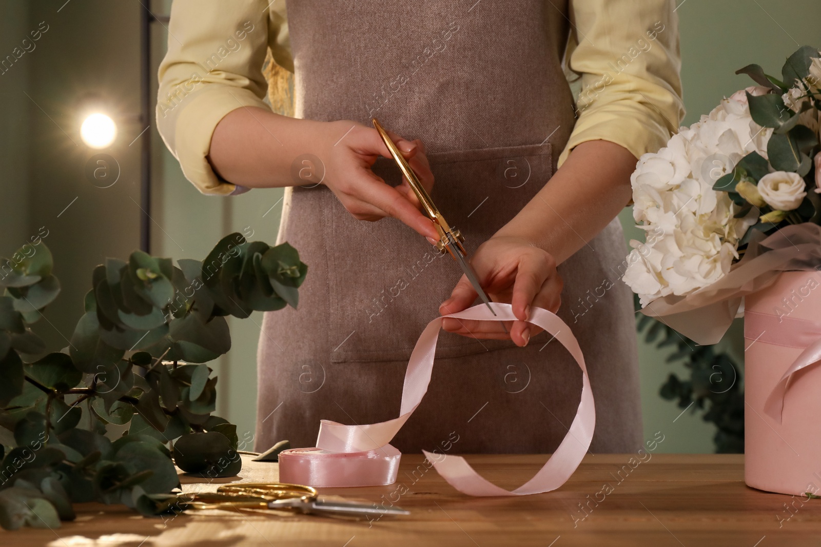 Photo of Florist making beautiful bouquet at table in flower shop, closeup