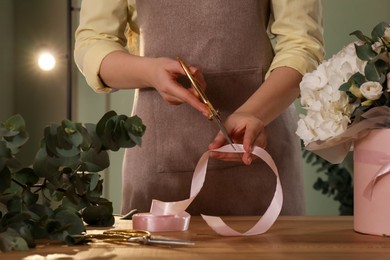 Photo of Florist making beautiful bouquet at table in flower shop, closeup