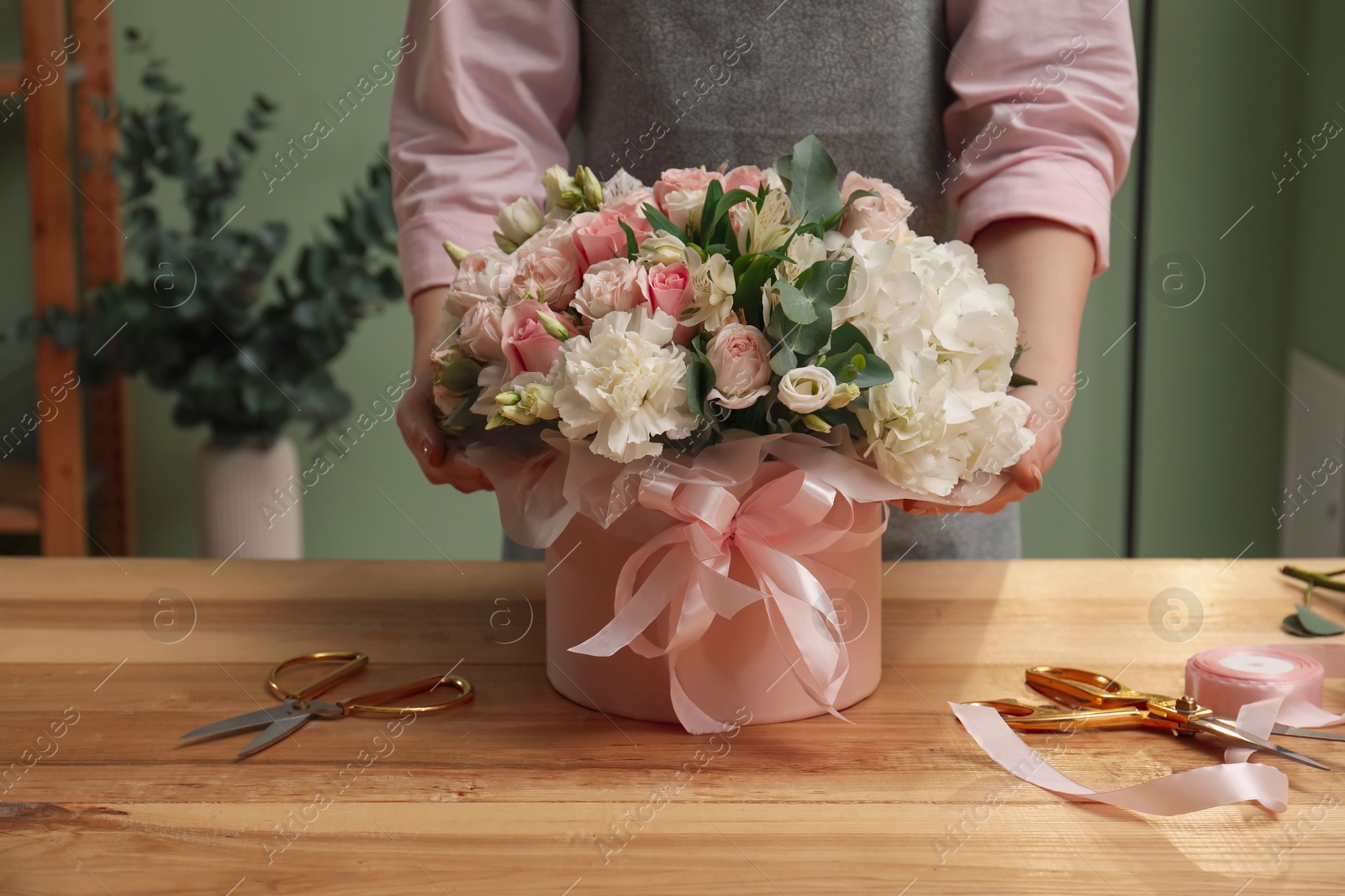 Photo of Florist with beautiful bouquet in box at table indoors, closeup