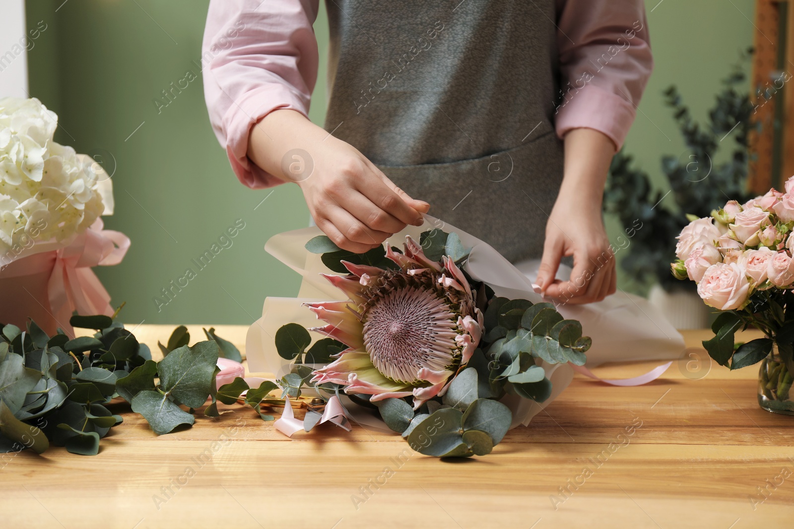 Photo of Florist making beautiful bouquet at table in flower shop, closeup