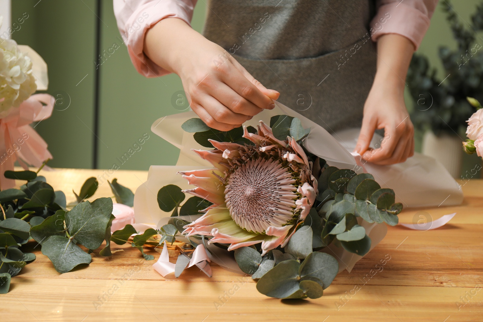 Photo of Florist making beautiful bouquet at table in flower shop, closeup