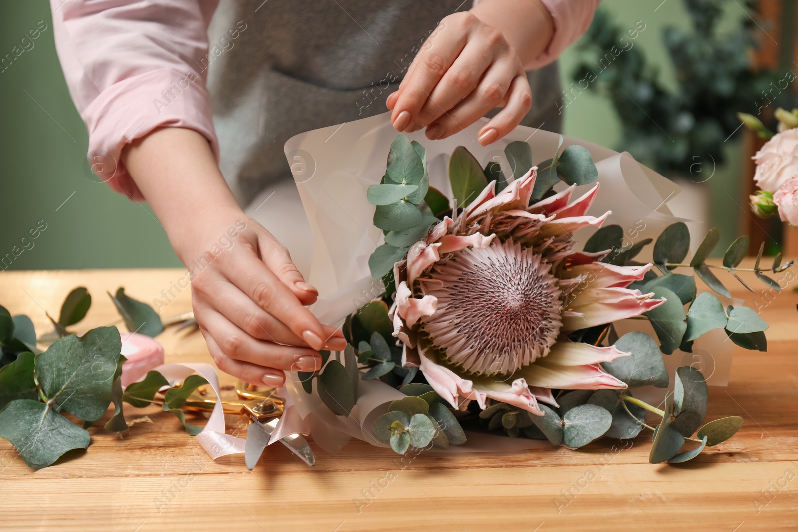 Photo of Florist making beautiful bouquet at table in flower shop, closeup