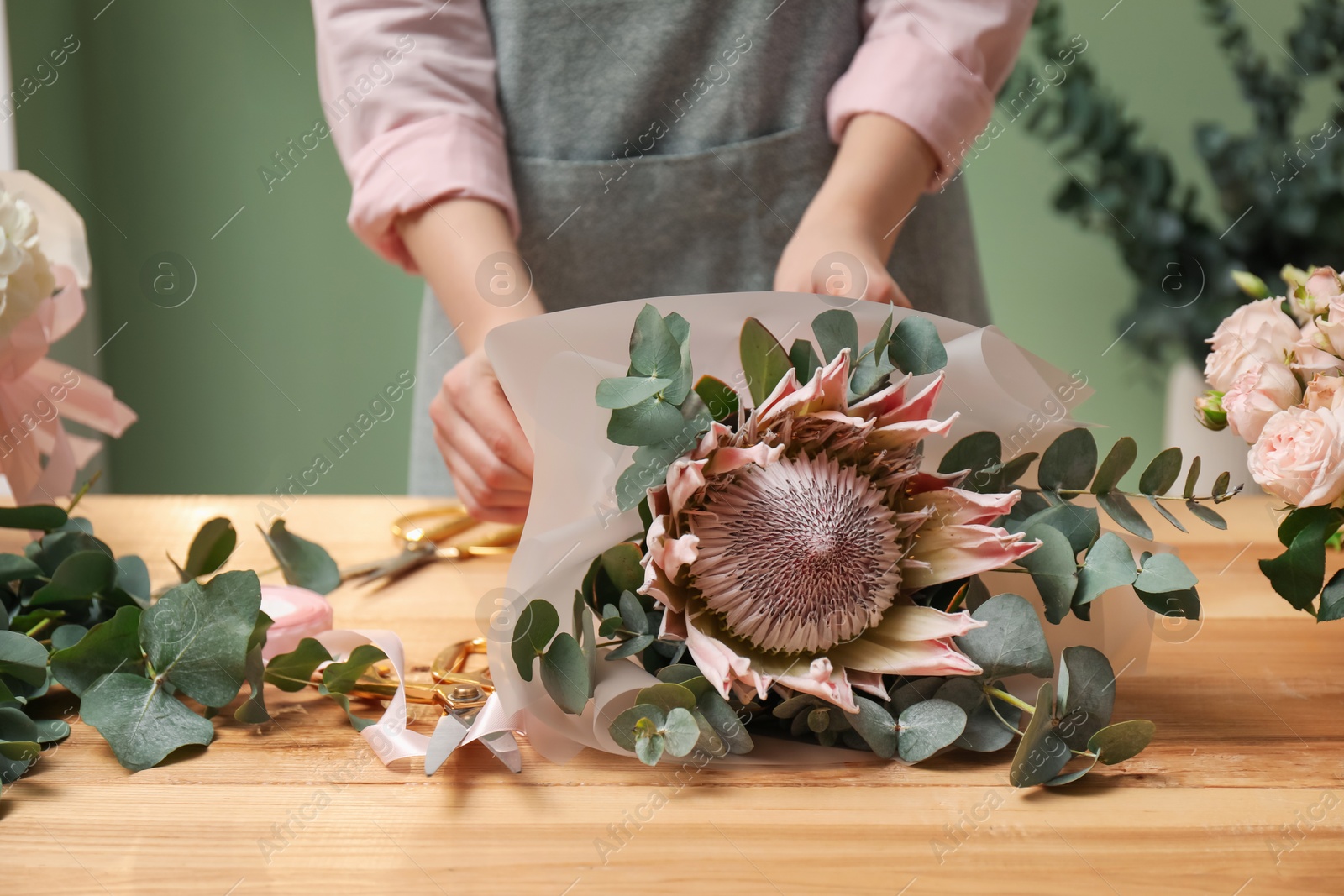 Photo of Florist making beautiful bouquet at table in flower shop, closeup