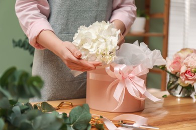 Photo of Florist making beautiful bouquet at table in flower shop, closeup