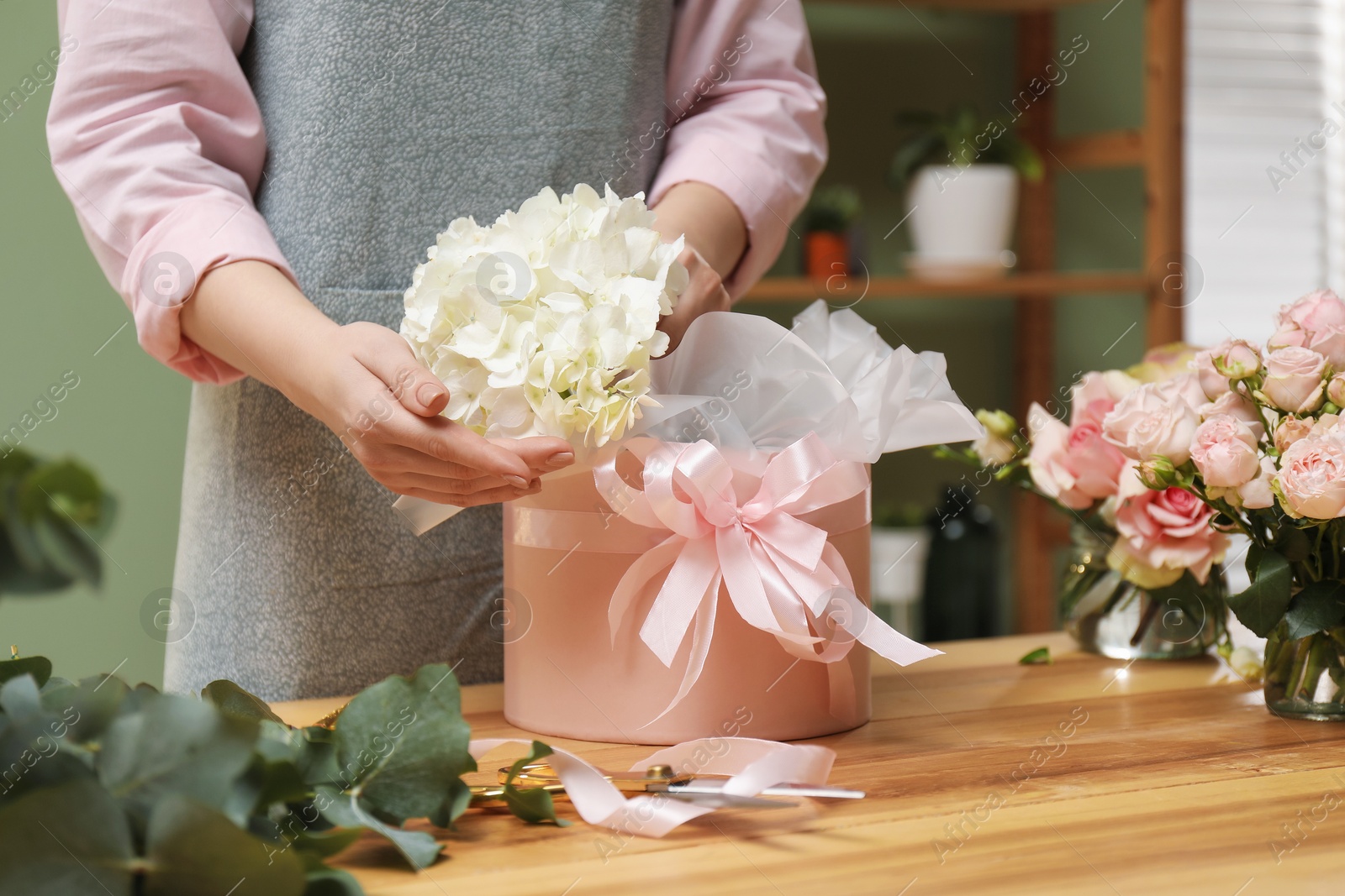 Photo of Florist making beautiful bouquet at table in flower shop, closeup