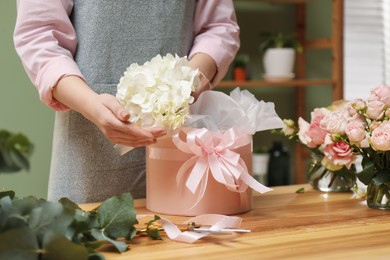 Photo of Florist making beautiful bouquet at table in flower shop, closeup