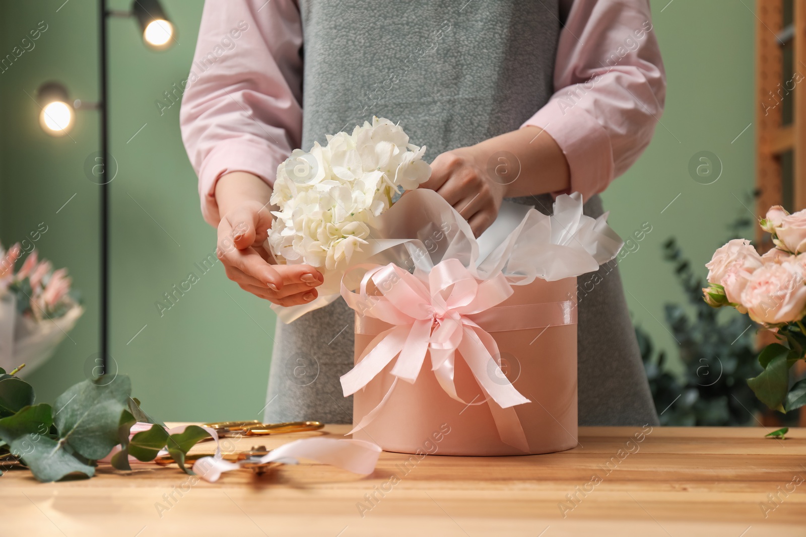 Photo of Florist making beautiful bouquet at table in flower shop, closeup