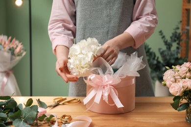 Photo of Florist making beautiful bouquet at table in flower shop, closeup