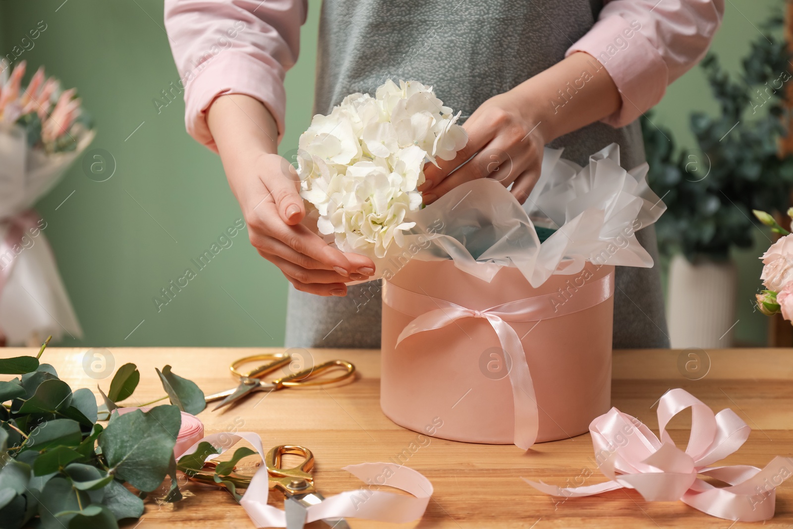 Photo of Florist making beautiful bouquet at table in flower shop, closeup