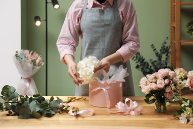 Photo of Florist making beautiful bouquet at table in flower shop, closeup