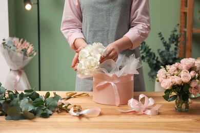 Photo of Florist making beautiful bouquet at table in flower shop, closeup