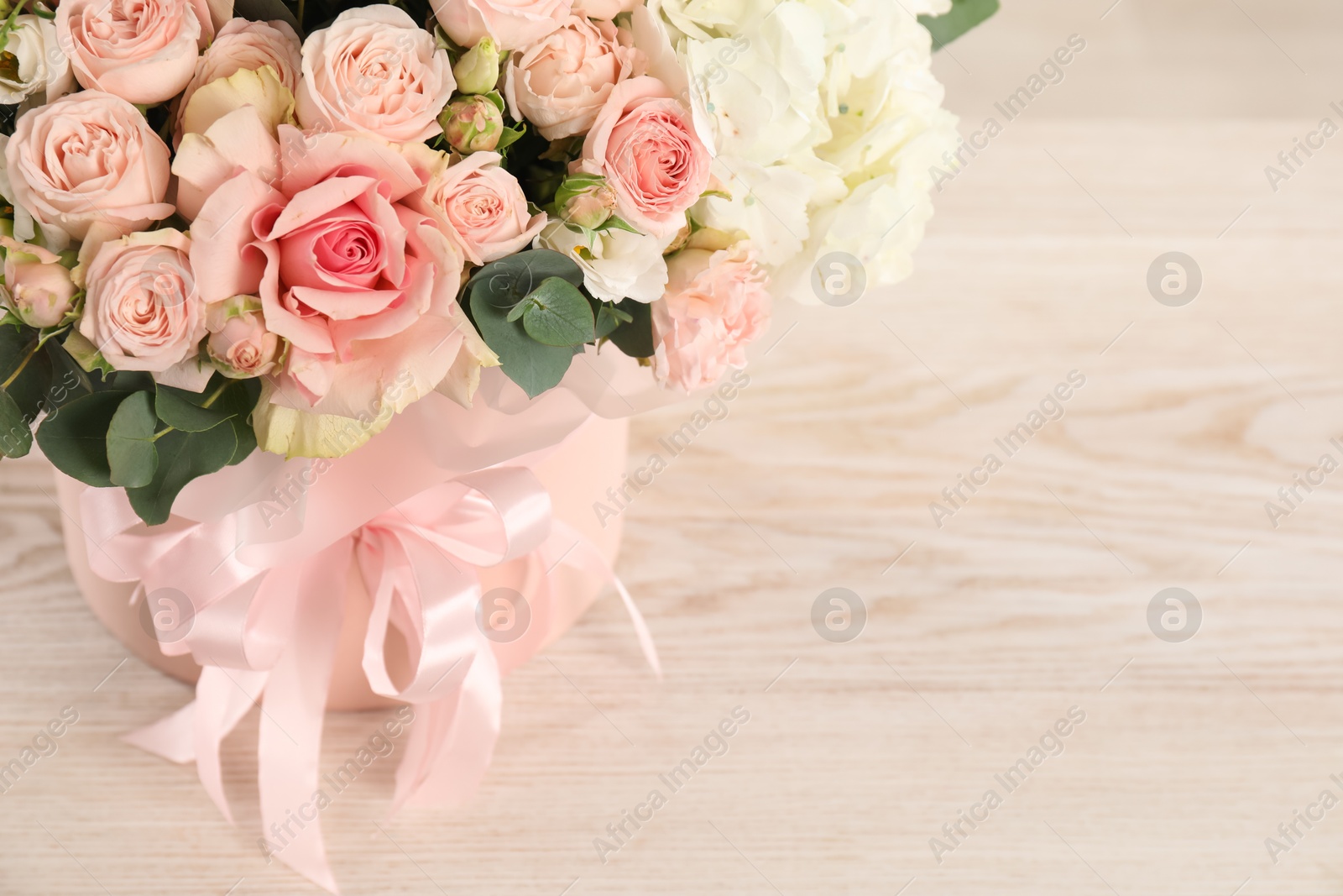 Photo of Beautiful bouquet in box on wooden table, closeup. Space for text