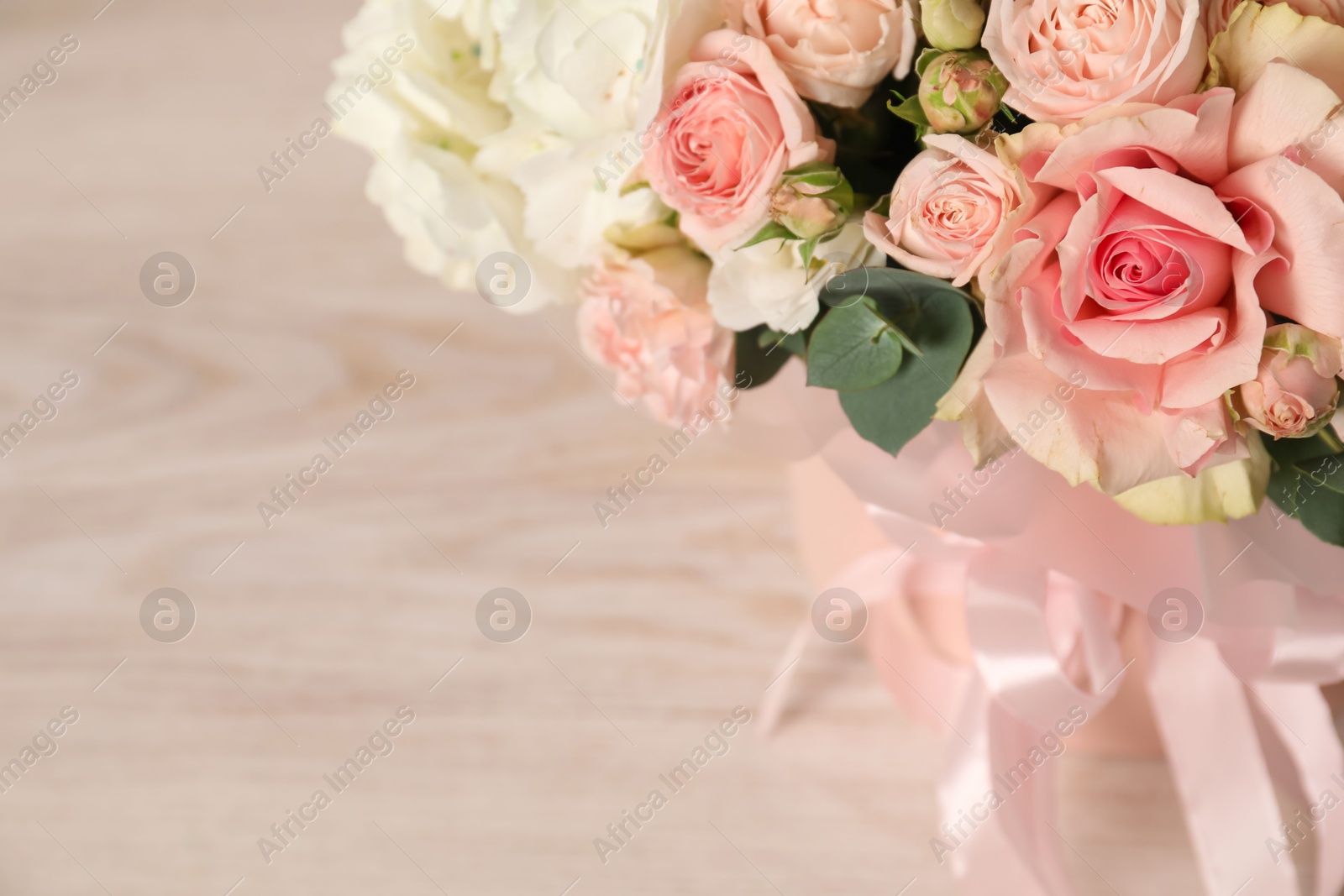 Photo of Beautiful bouquet in box on wooden table, closeup. Space for text