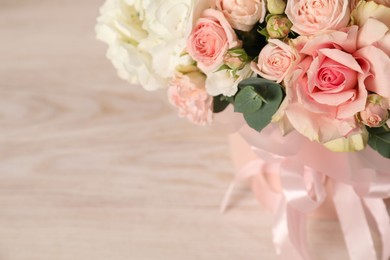 Photo of Beautiful bouquet in box on wooden table, closeup. Space for text